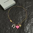 Gold-tone chain necklace with horseshoe charm, pink heart charm, and B pendant