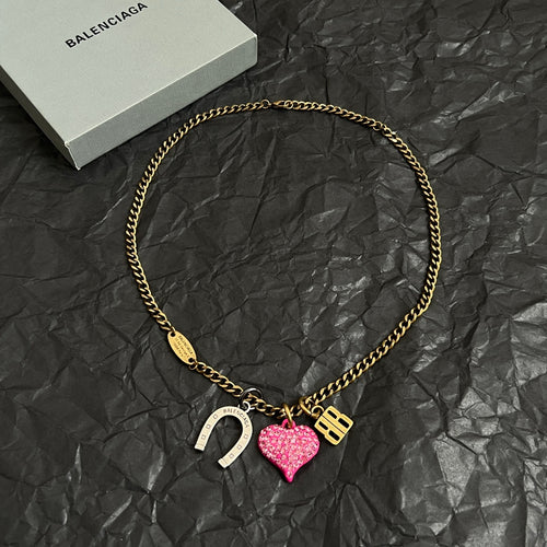 Gold-tone chain necklace with horseshoe charm, pink heart charm, and B pendant