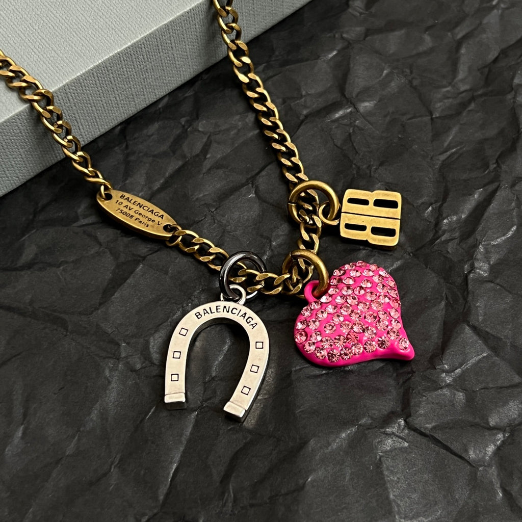 Gold-tone necklace with pink heart charm, horseshoe charm, and B pendant detail