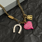 Gold-tone necklace with pink heart charm, horseshoe charm, and B pendant detail