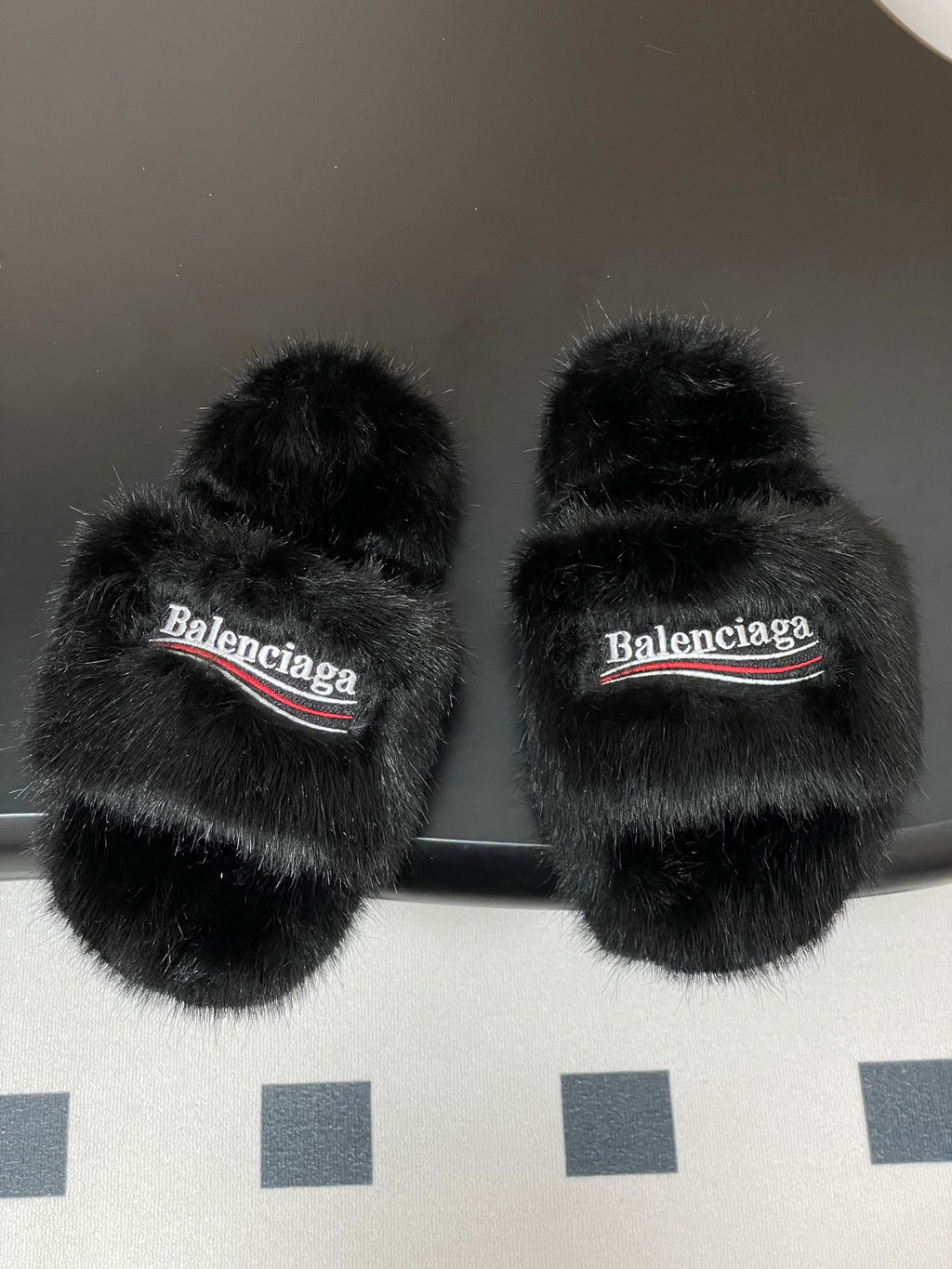 Black fuzzy slide sandals with two crossover straps and Balenciaga logo band
