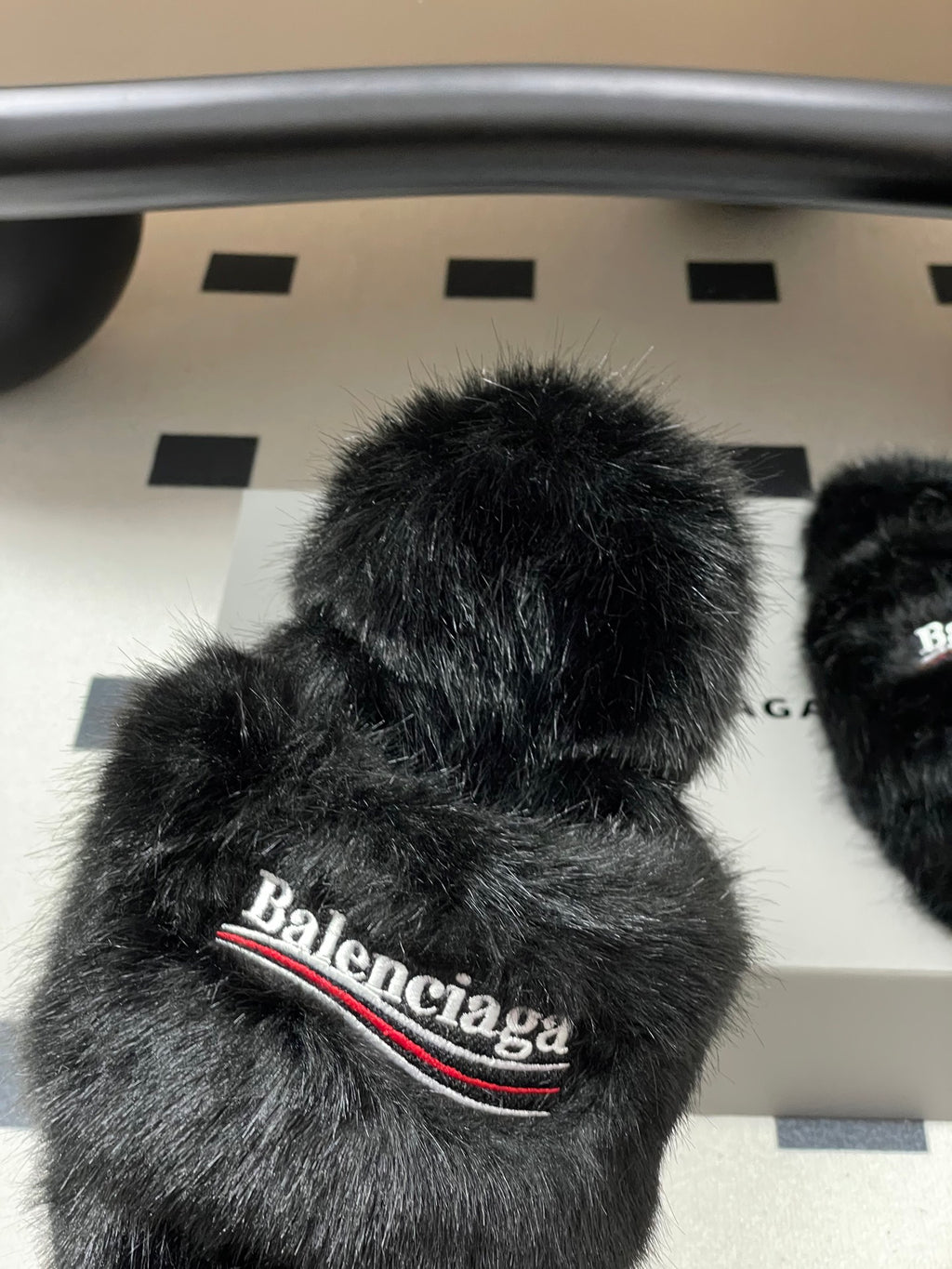 Black fuzzy slide sandal close-up with Balenciaga logo band on front strap