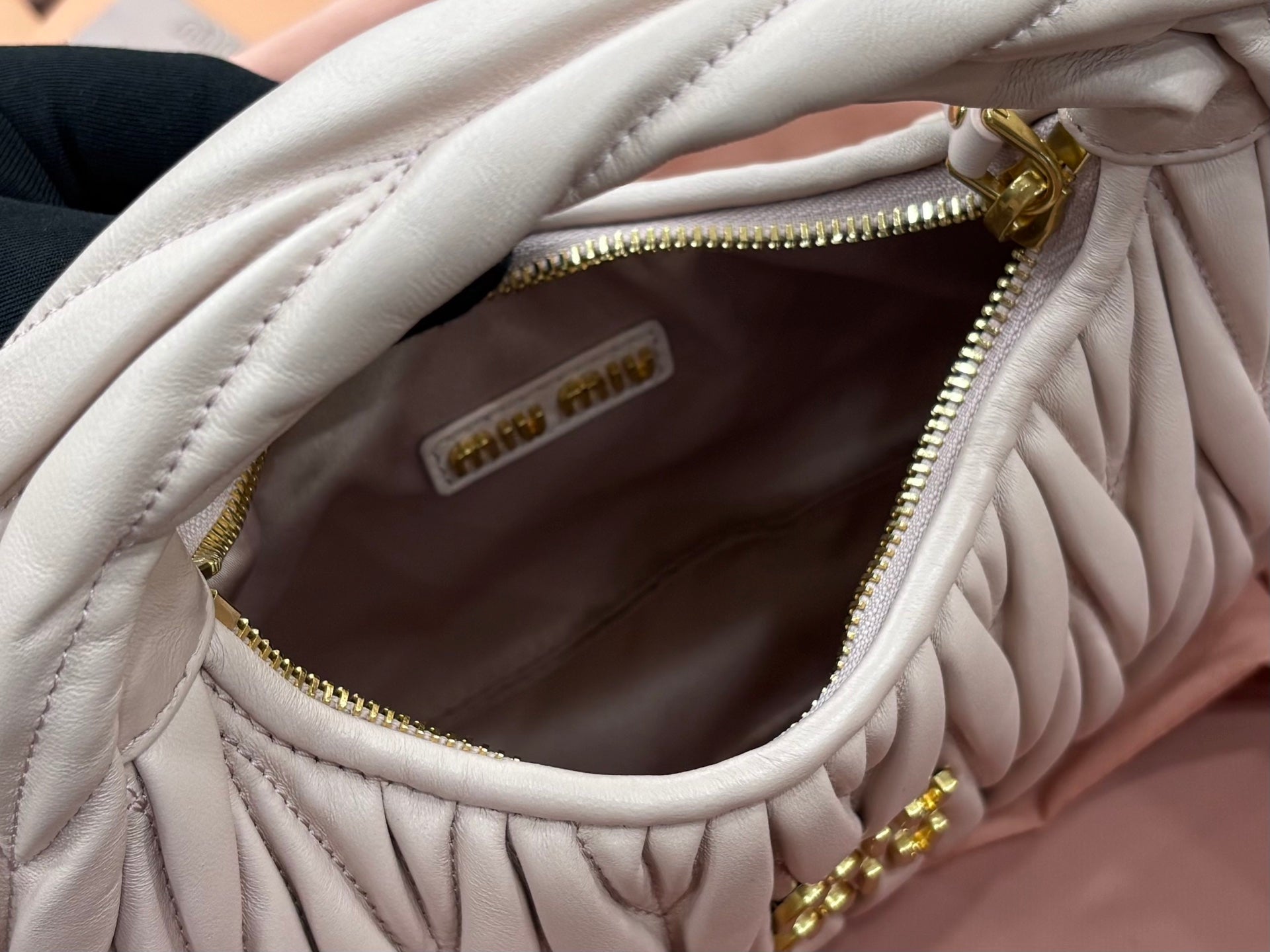 MiuMiu cream quilted bag interior view with zip pocket and gold zipper trim