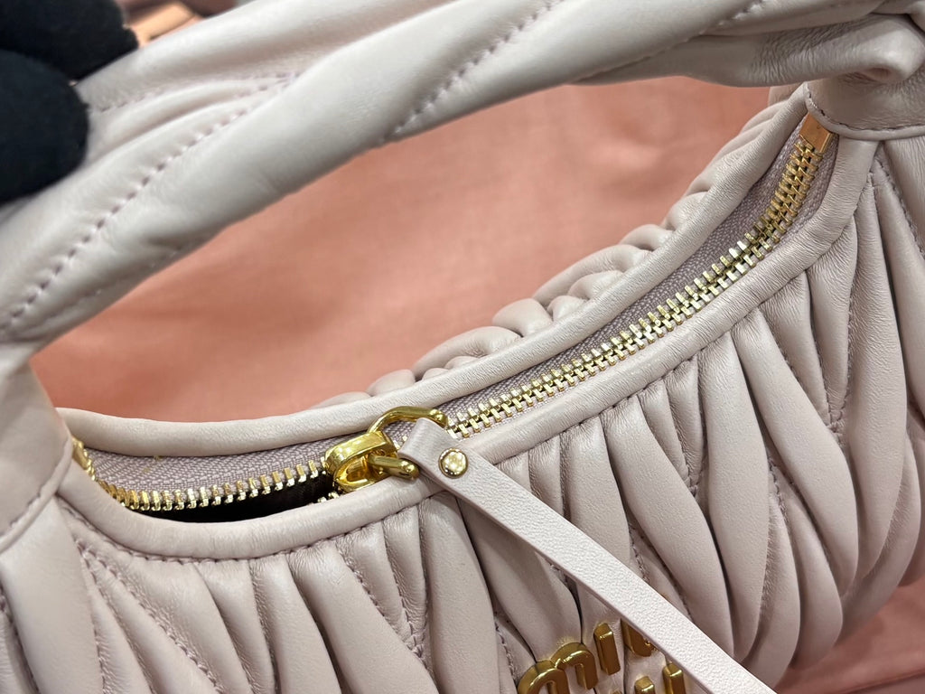 MiuMiu cream quilted bag close-up of gold zipper and front drawstring tab