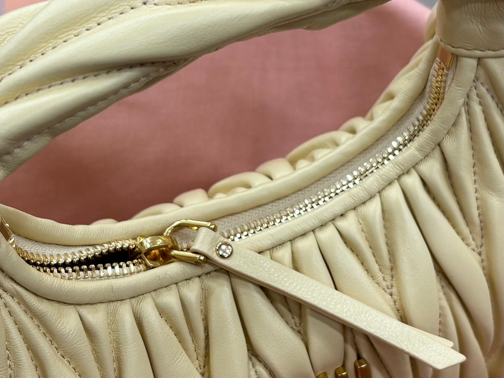MiuMiu pale yellow mini hobo bag with front zipper, braided trim, and gold hardware