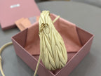 MiuMiu mini hobo bag side view in pale yellow leather with structured ruched body