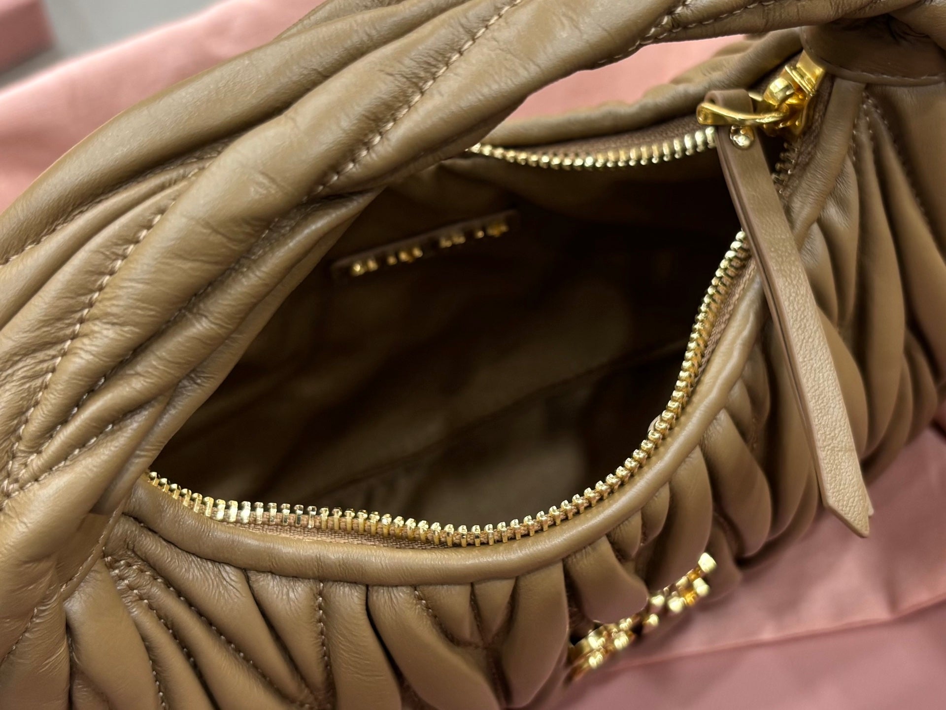 MiuMiu olive green mini bag with open zipper showing inner compartment