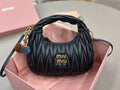 Black leather MiuMiu handbag with ruched panels, gold logo, top handles, and side strap