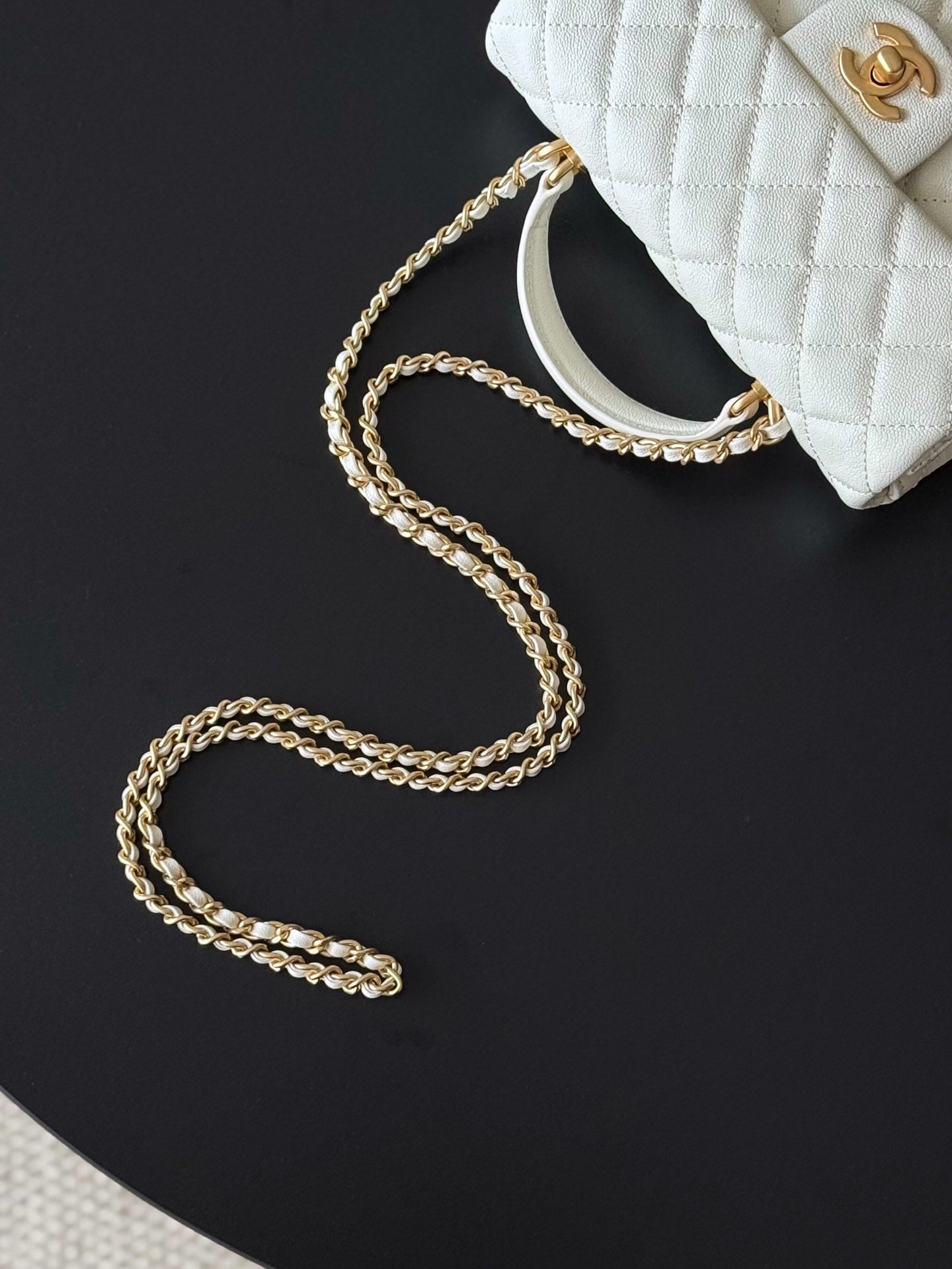 White mini handbag with gold-tone chain strap laid out for display