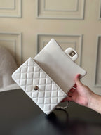 Chanel quilted white flap bag held in hand with gold-tone clasp