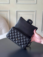 Chanel quilted leather mini bag held by hand, black with chain strap