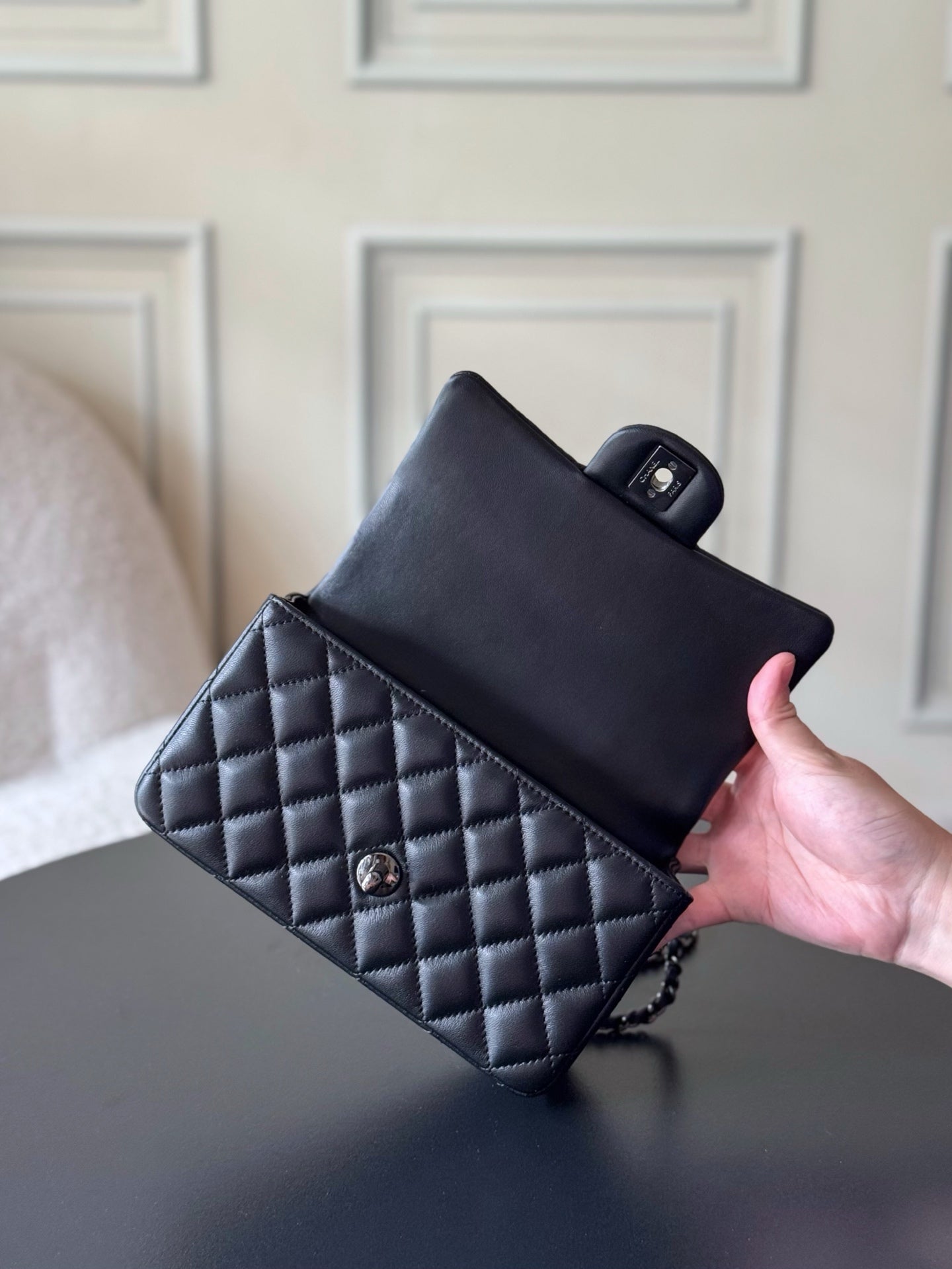 Chanel quilted leather mini bag held by hand, black with chain strap
