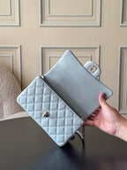 Chanel bag light blue quilted mini with top handle and logo flap, held in hand