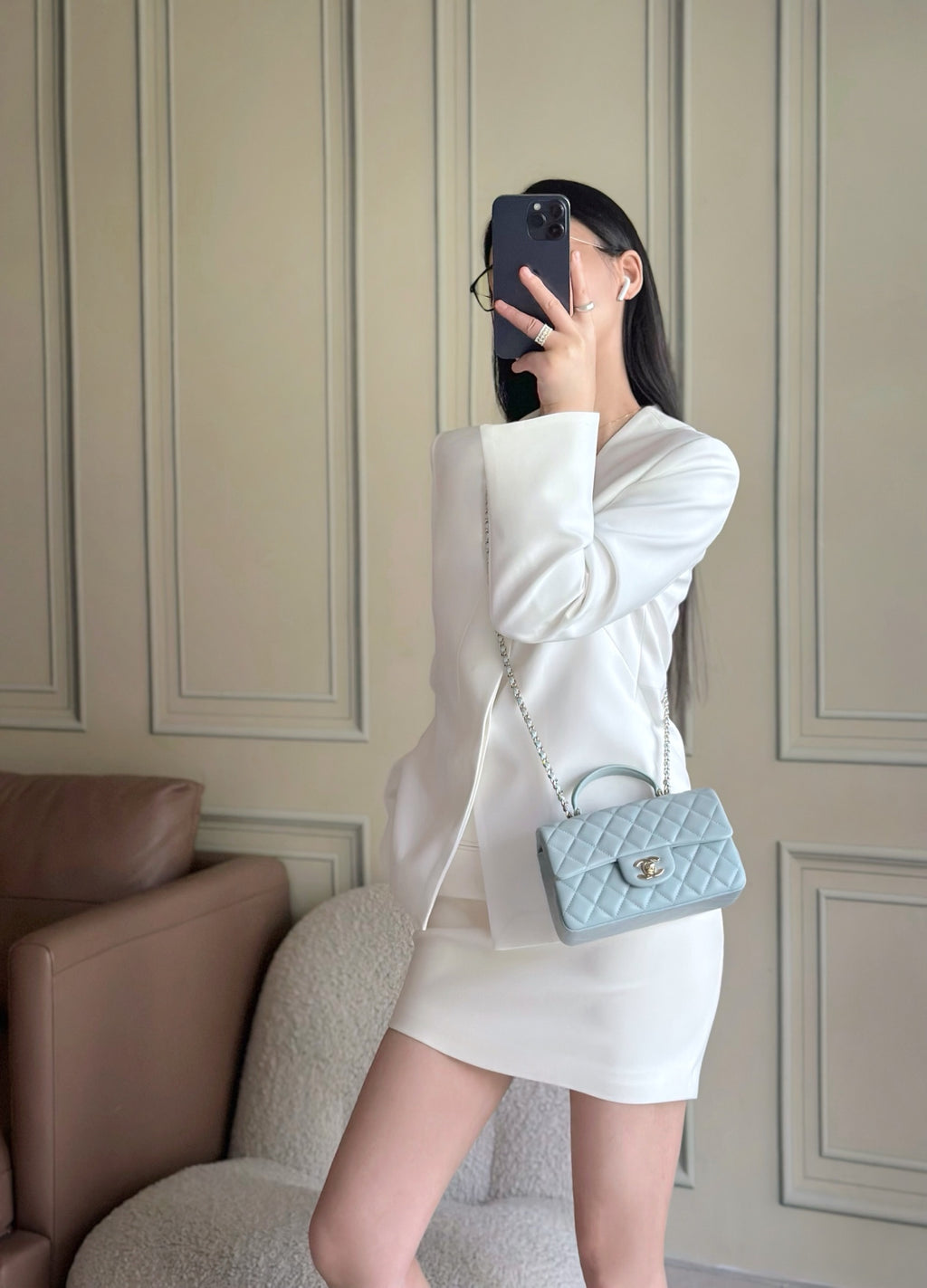Chanel bag in light blue quilted mini on chain strap, worn crossbody with flap logo