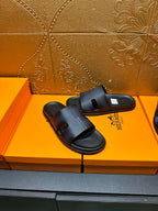 Hermes dark leather slide sandals with wide strap and open toe, on display