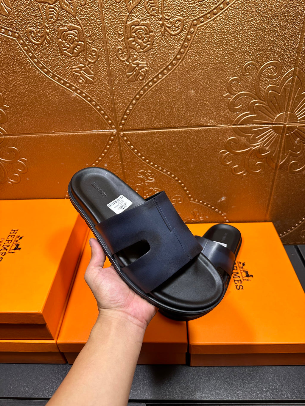 Hermes dark blue slide sandal held in hand, open toe and wide strap
