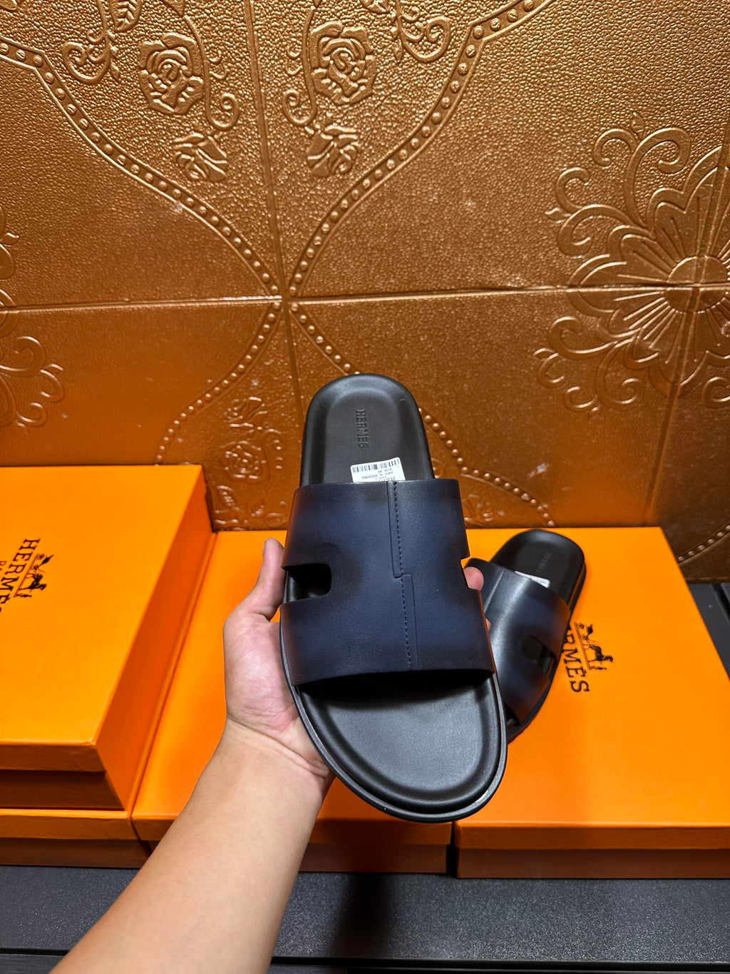 Hermes dark blue leather slide sandal held in hand, top view of footbed