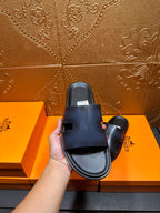 Hermes dark blue leather slide sandal held in hand, top view of footbed