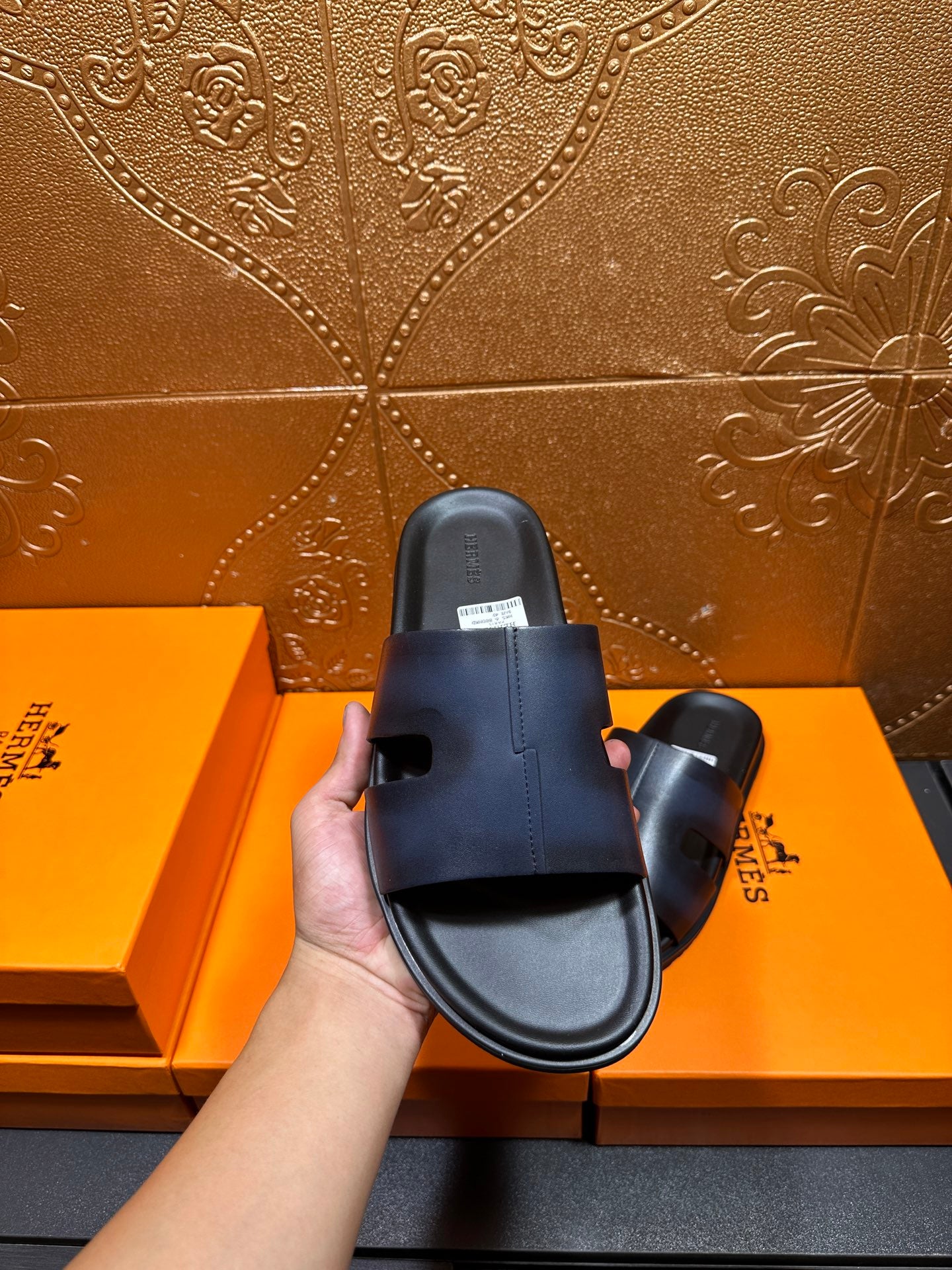 Hermes dark blue leather slide sandal held in hand, top view of footbed