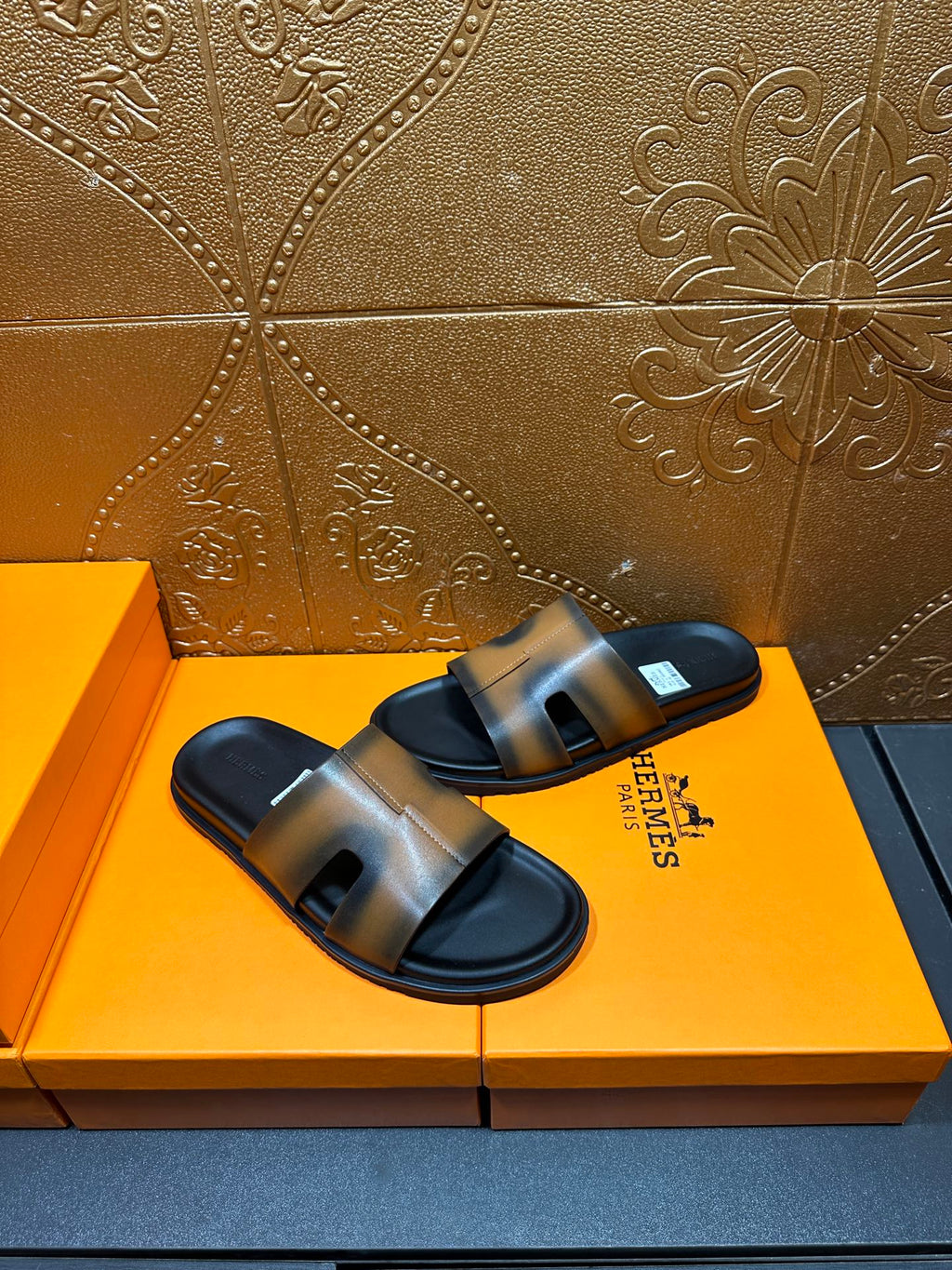 Hermes slide sandals on box, gray-tan straps with dark open-toe soles