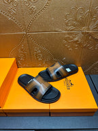 Hermes slide sandals on box, gray-tan straps with dark open-toe soles