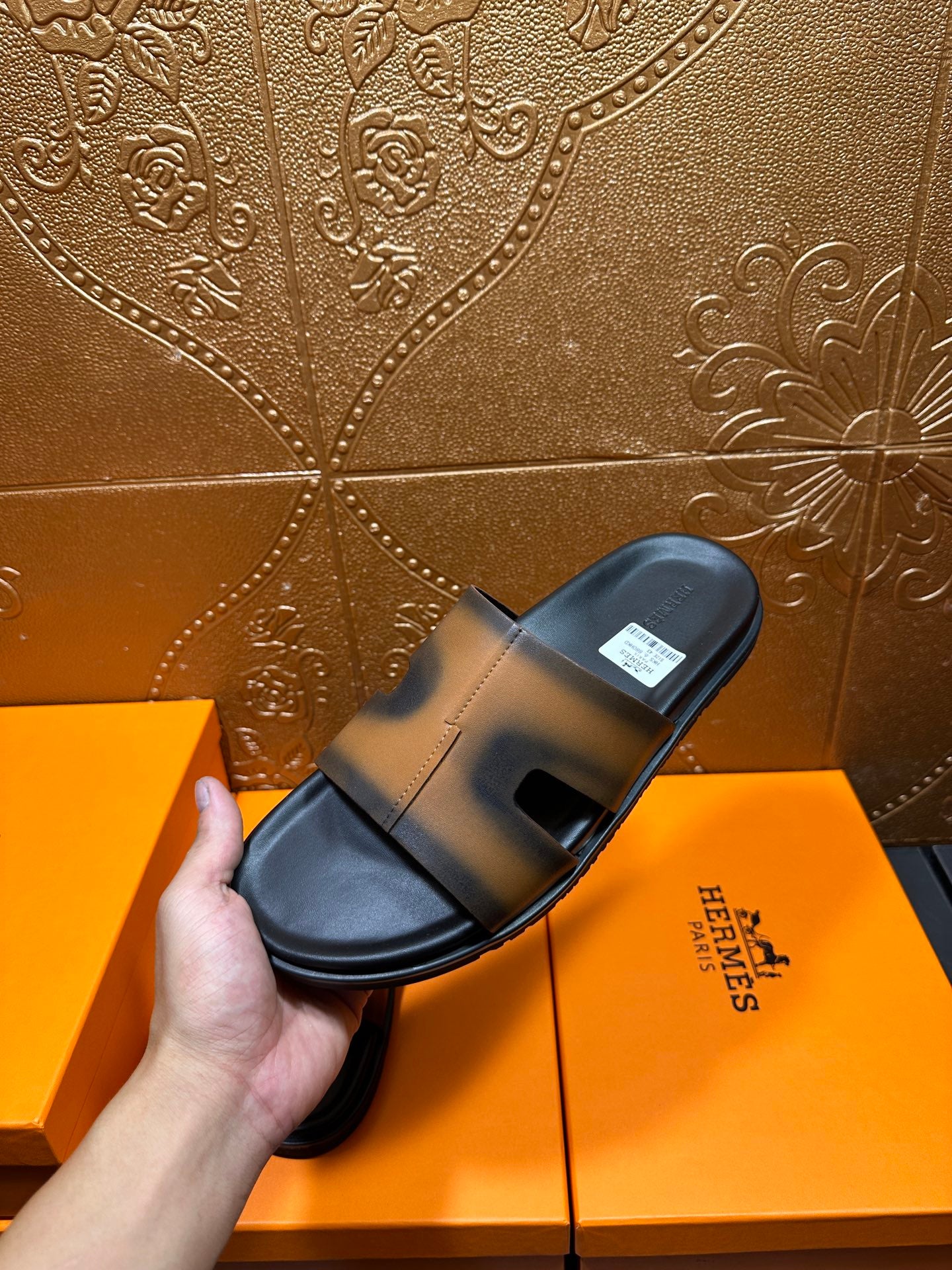 Hermes slide sandal held in hand, gray-tan strap with black sole