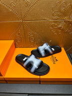 Hermes slide sandals on orange box, metallic blue strap and black sole pair