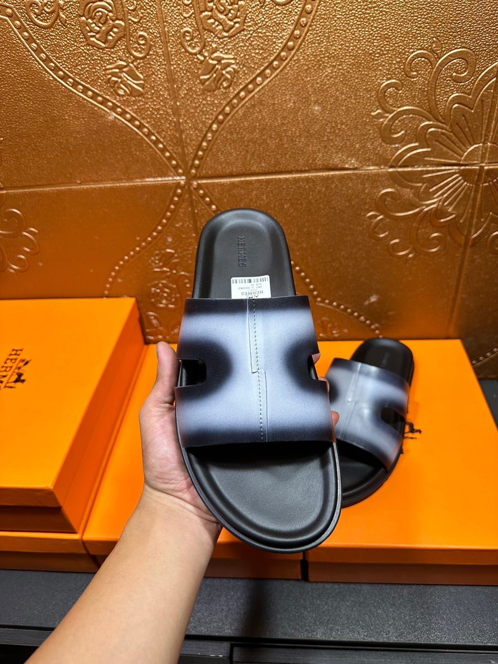 Hermes slide sandal in hand, black outsole and metallic blue strap