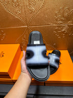 Hermes slide sandal in hand, black outsole and metallic blue strap