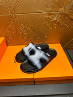 Hermes slide sandals with metallic blue upper and black outsole, angled view