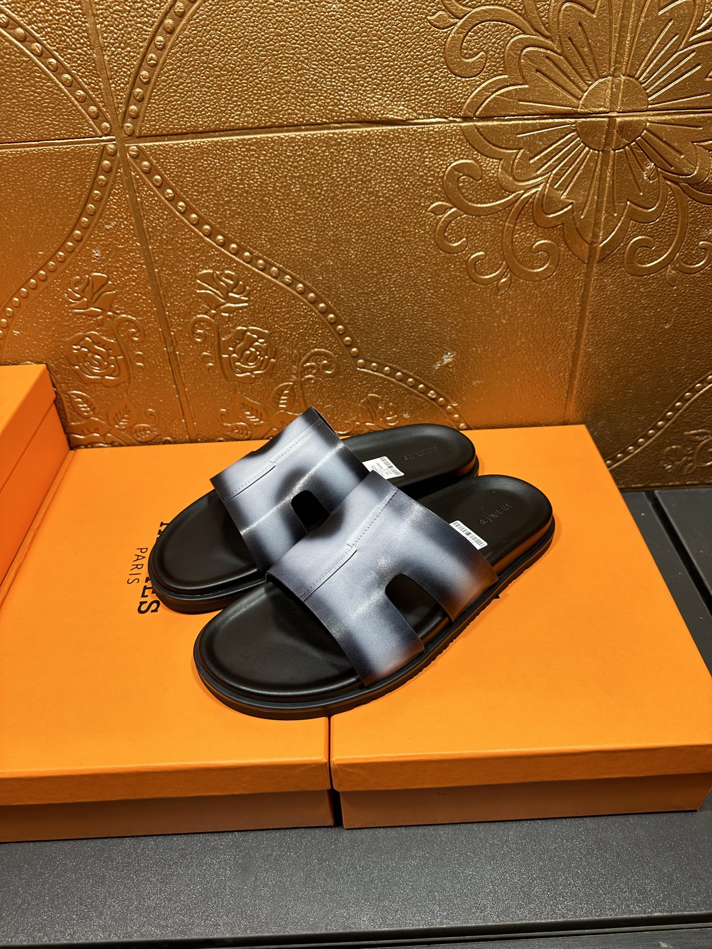 Hermes slide sandals with metallic blue upper and black outsole, angled view