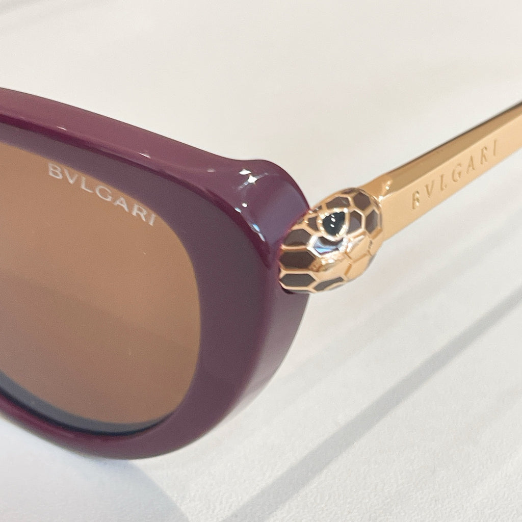 Bvlgari sunglasses close-up: burgundy frame with gold-tone decorative hinge and lens