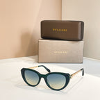 Bvlgari sunglasses with dark green frames and blue-tinted oval lenses, gold-tone detail