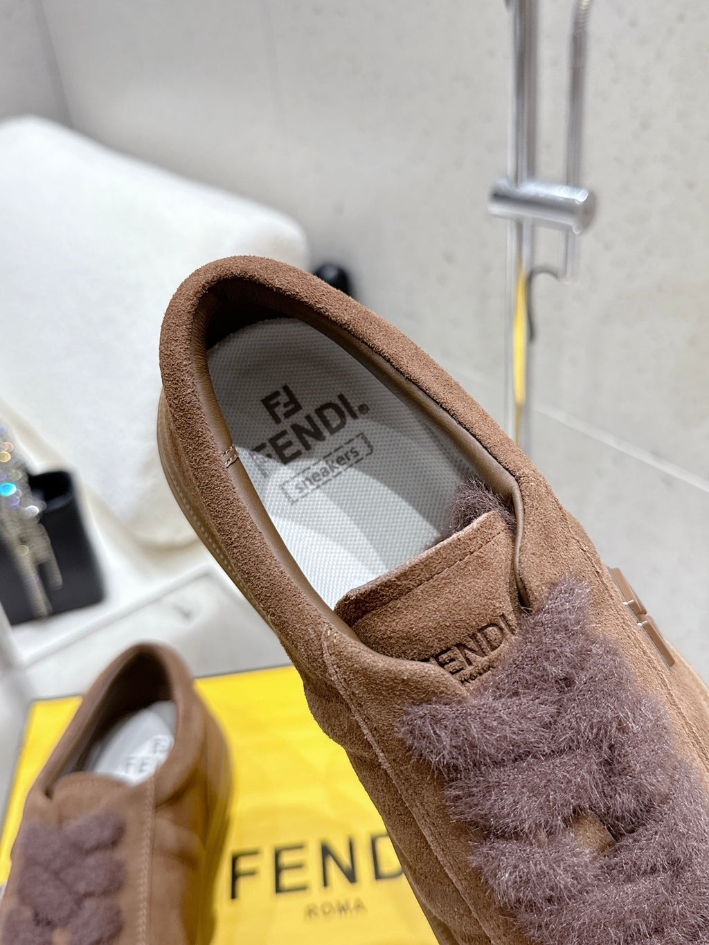 Brown suede sneaker showing fuzzy tongue and Fendi-branded interior lining