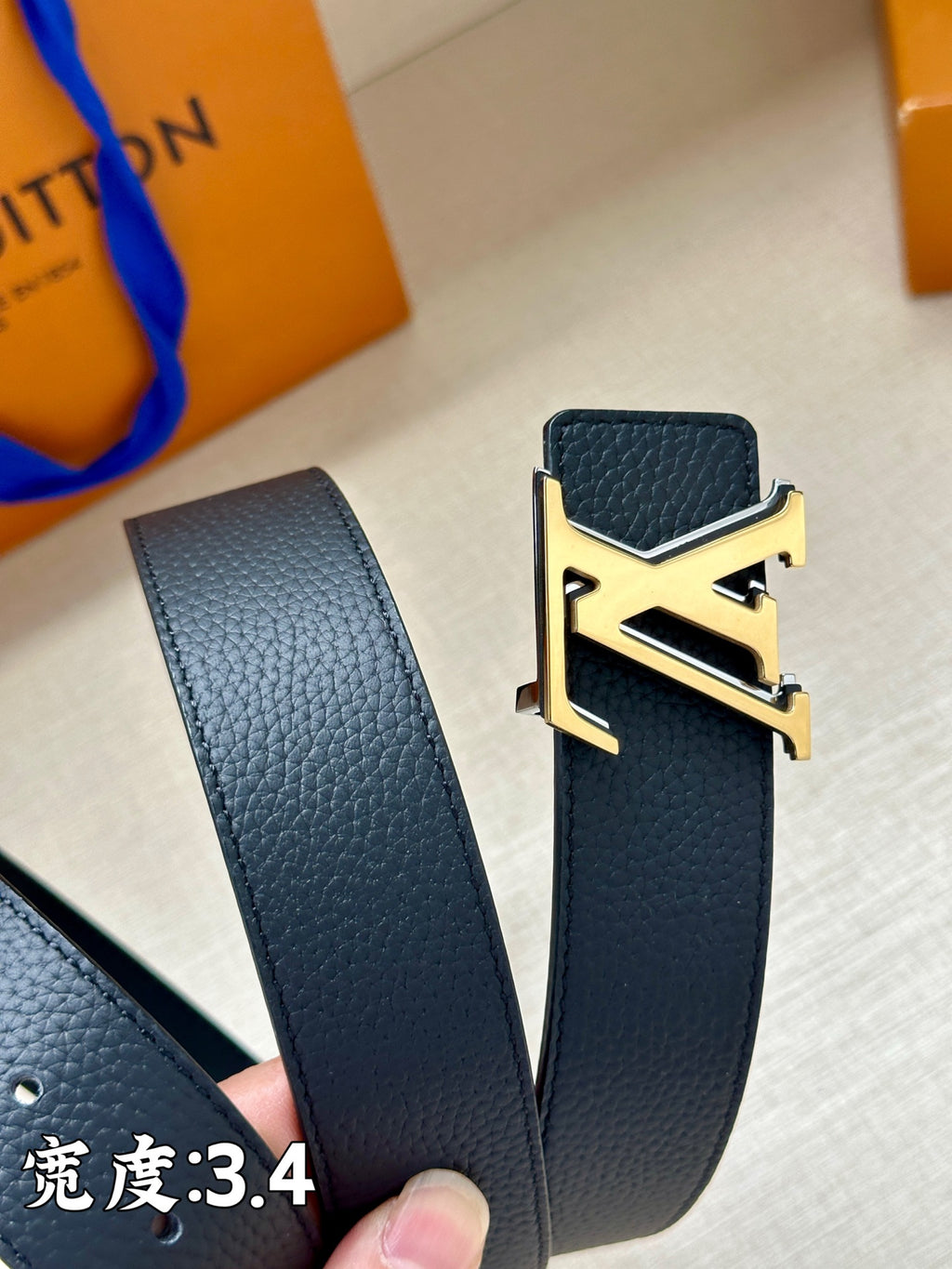 Louis Vuitton belt detail: dark blue leather strap and gold-tone LV buckle