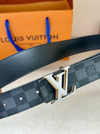 Monogram belt close-up: dark blue check strap with gold-tone V buckle