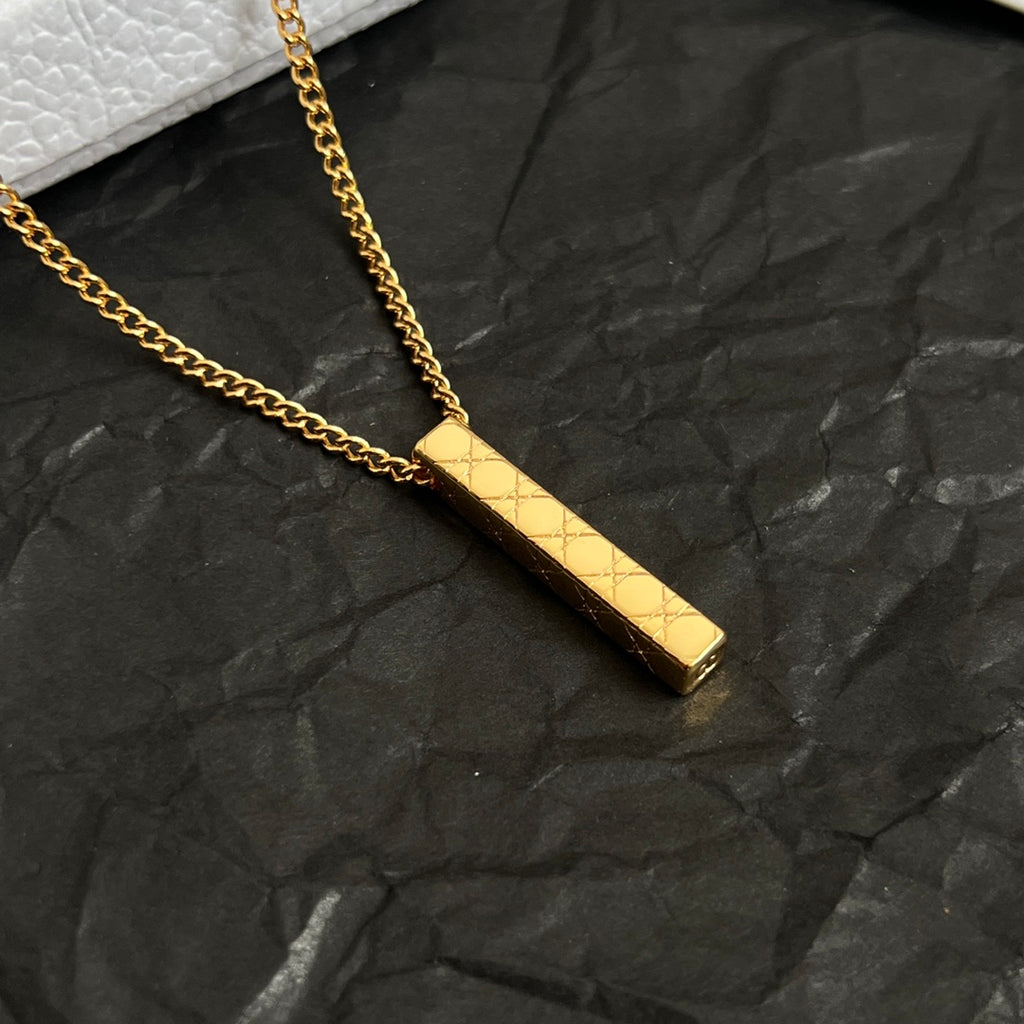 Close-up of gold-tone rectangular bar pendant on a chain
