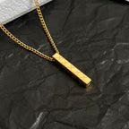 Close-up of gold-tone rectangular bar pendant on a chain