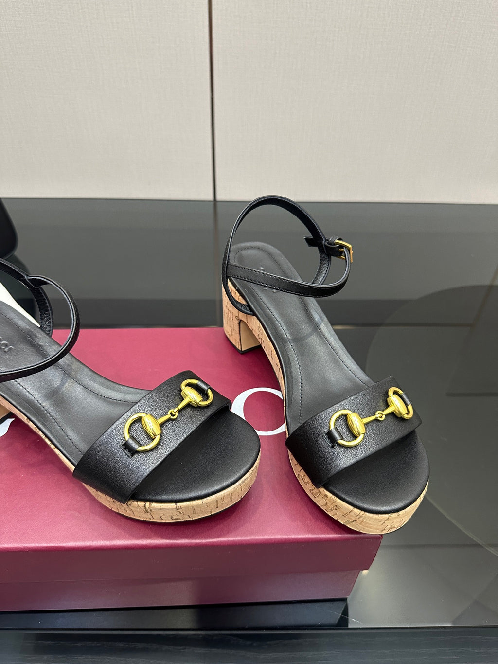 Close view of black platform sandals with gold buckle straps and cork soles