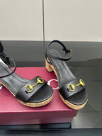 Close view of black platform sandals with gold buckle straps and cork soles