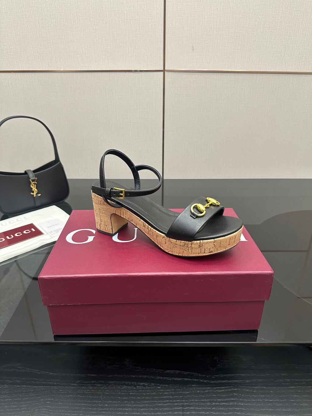 Side view of black heeled sandals with gold buckle details and cork platform