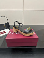 Side view of black heeled sandals with gold buckle details and cork platform