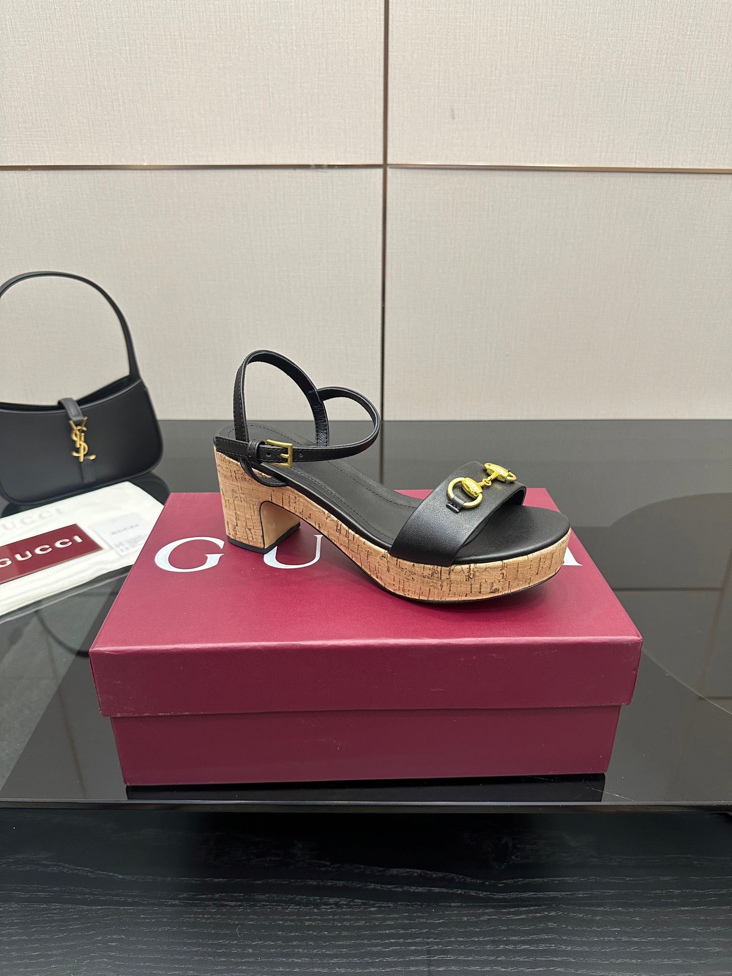 Side view of black heeled sandals with gold buckle details and cork platform