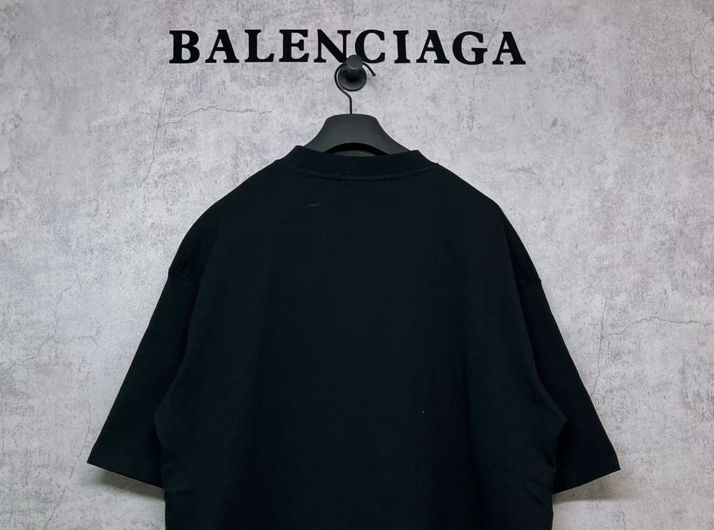 Black T-shirt back view with curved shoulder yoke, hanging on hanger