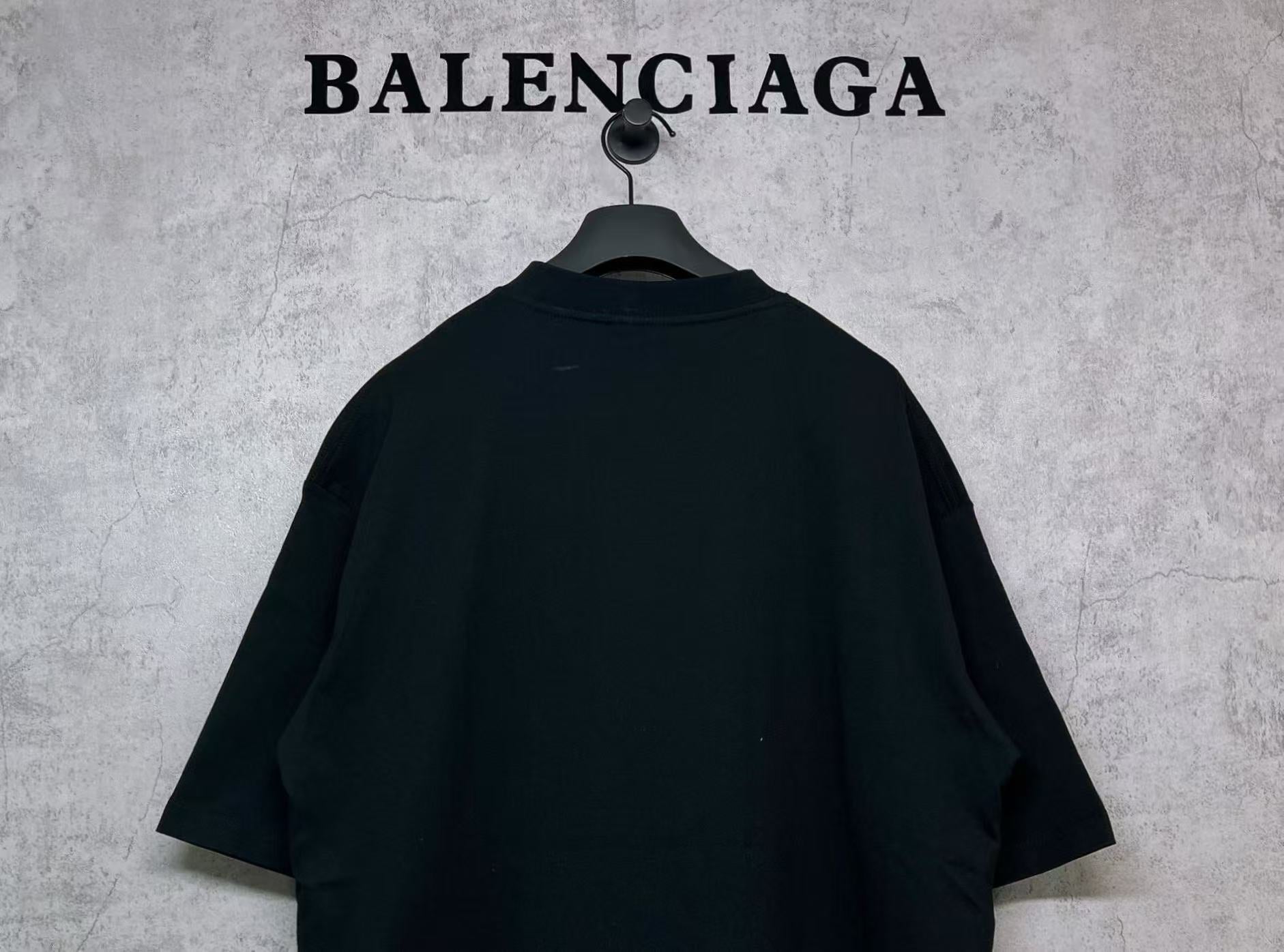 Black T-shirt back view with curved shoulder yoke, hanging on hanger