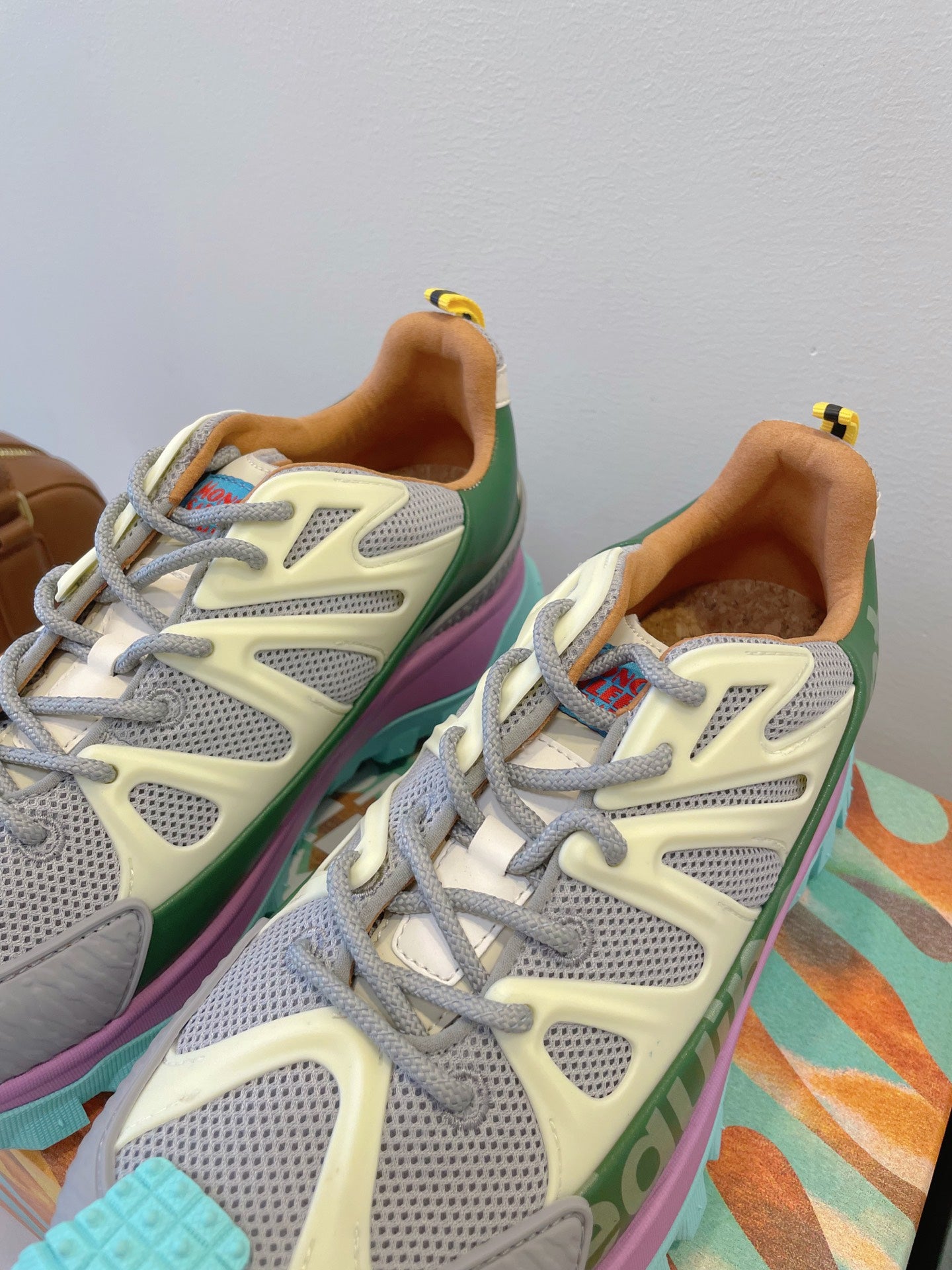 Moncler close-up sneakers: white-gray mesh uppers, green side panel, purple trim, laces