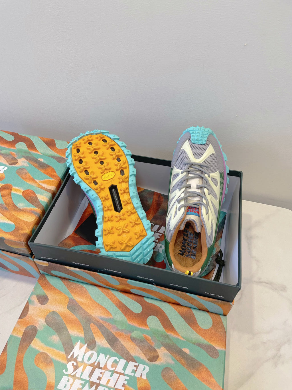 Moncler sneakers with blue textured outsoles, white-gray uppers, green collar, laces
