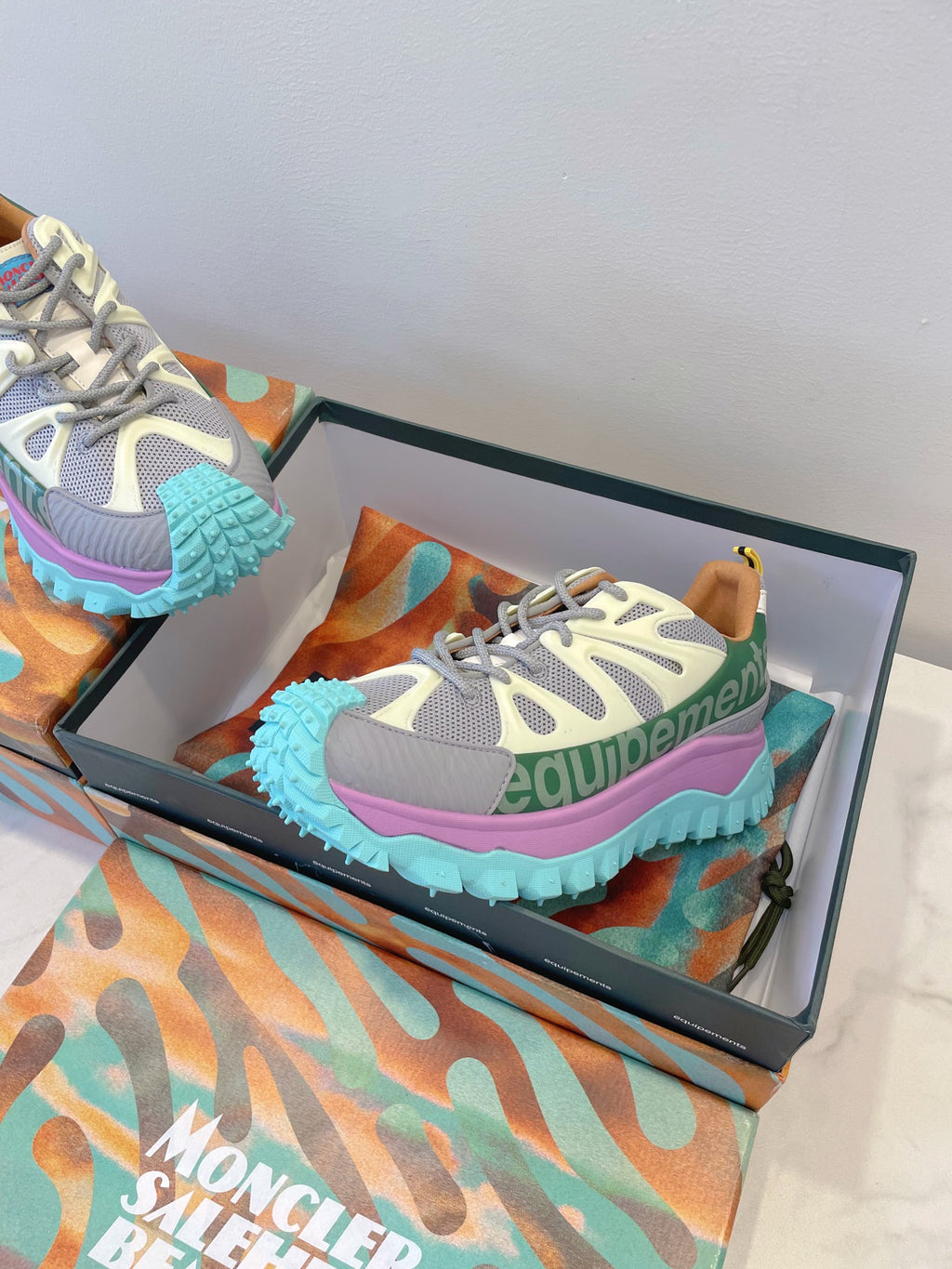 Moncler sneakers in box: white-gray mesh with green panels, pink outsole edge, teal tread