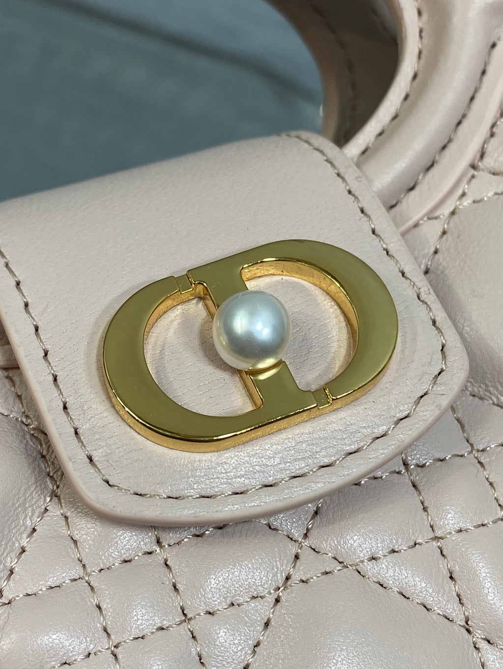 Dior handbag clasp with round pearl and gold-tone frame on pale pink leather