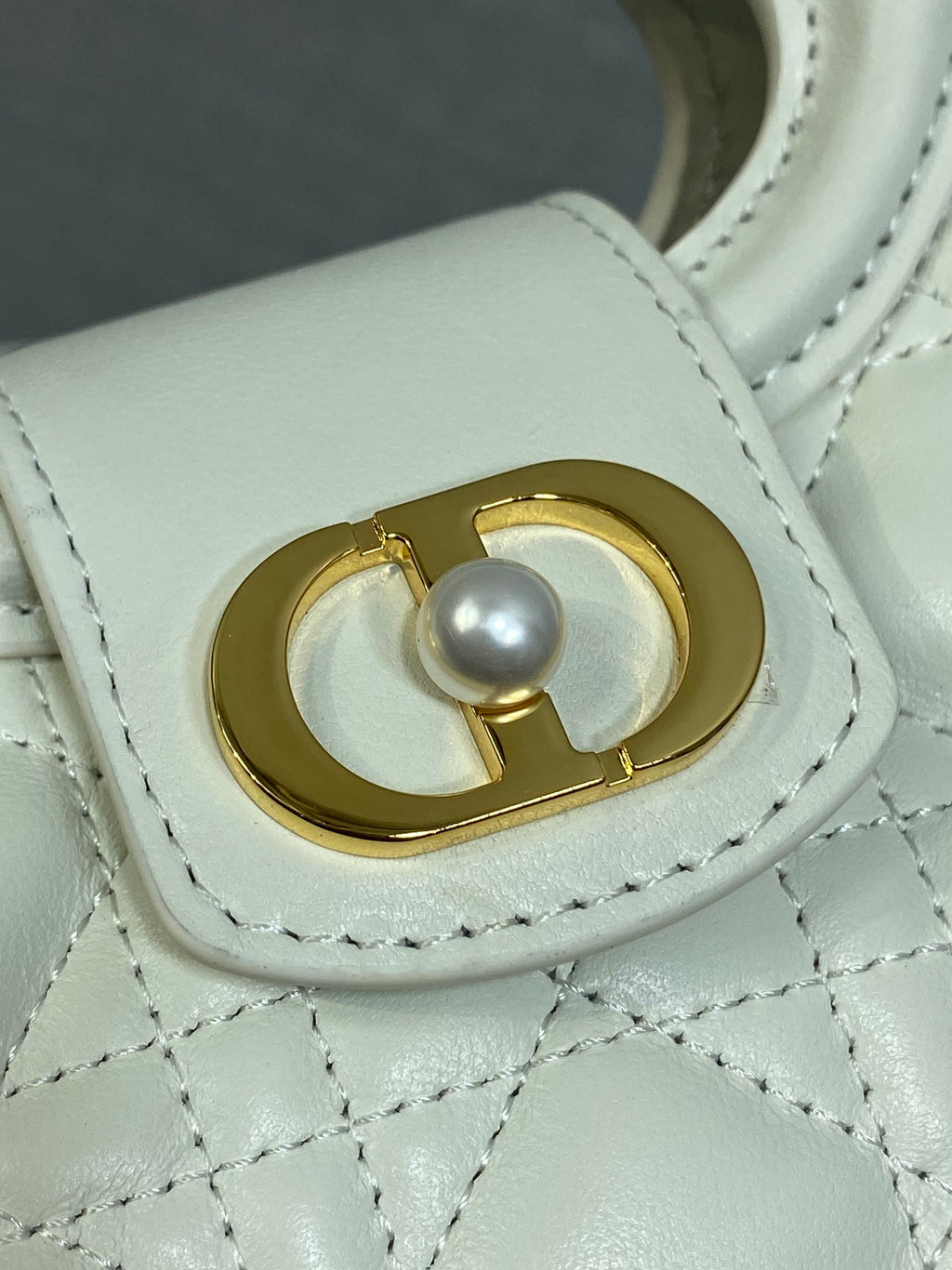 Dior quilted mini handbag close-up of gold clasp with pearl accent and stitching